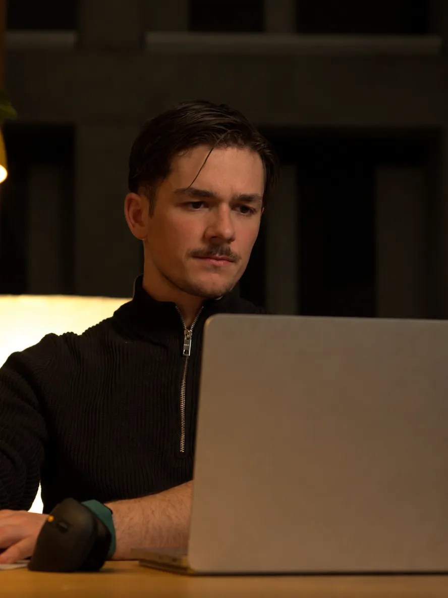 Lars arbeitet abends am Laptop, warme Lampe
